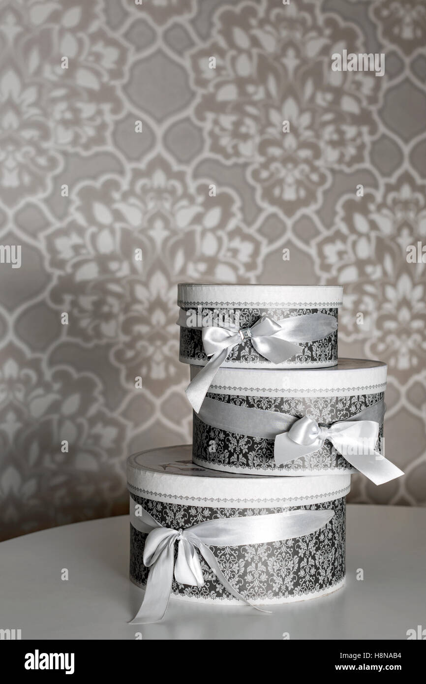 Three round celebration gift boxes with silver ribbon bows on white
