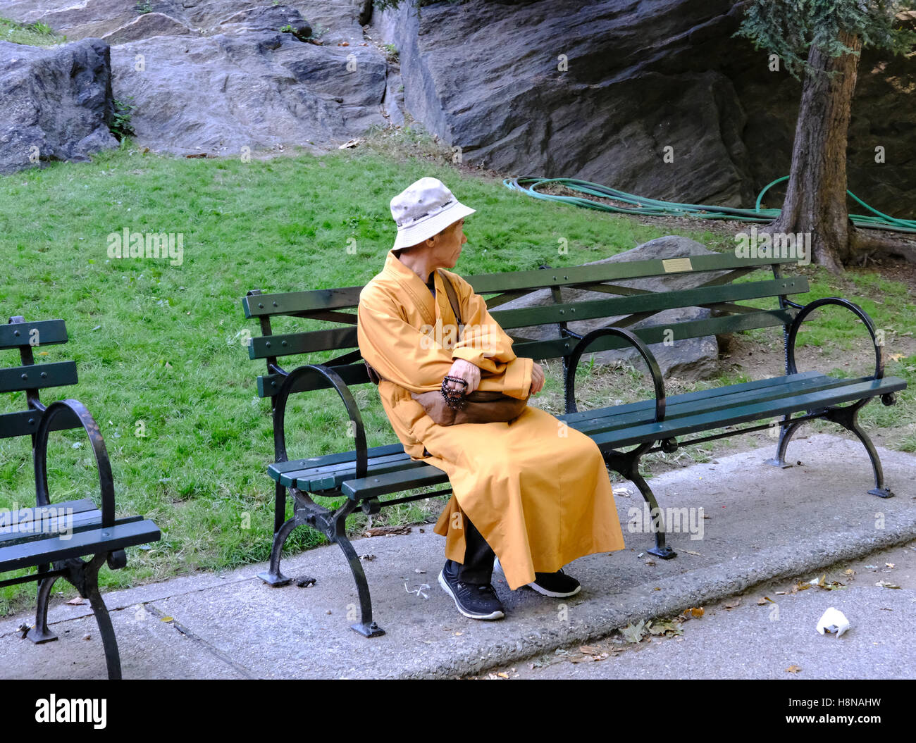 Buddhist monk seen sitting on a chair, waiting for passers by in