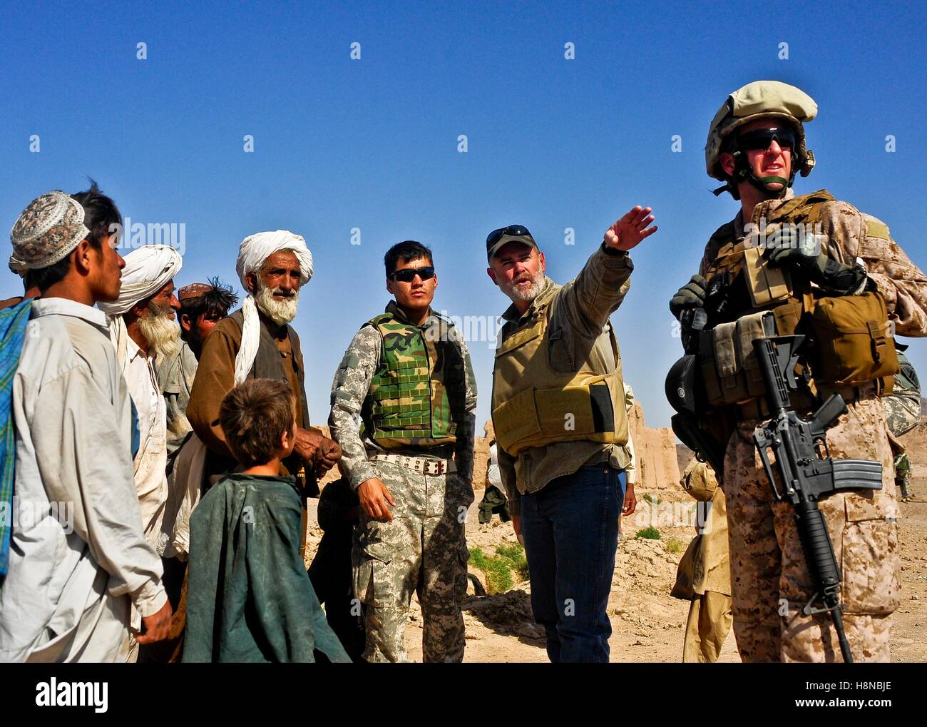 U.S. Marine soldiers and Afghan locals from the Kuchi tribe listen as U.S. Department of Agriculture advisor Darren Richardson points to a nearby canal June 12, 2010 in the Bawka district, Farah province, Afghanistan. Stock Photo