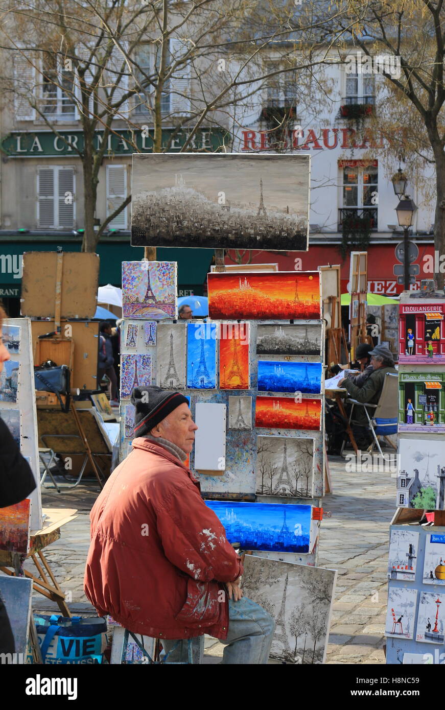 Artist sitting with his oil paintings on a sunny winter day in Montmartre, Paris Stock Photo
