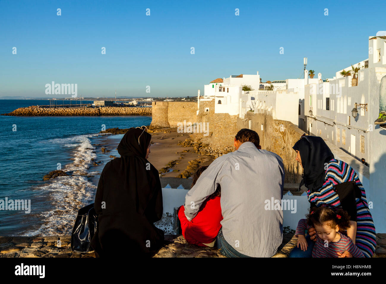 Moroccan People Look Out Over The Walled Medina Of Asilah At Sunset, Asilah, Morocco Stock Photo