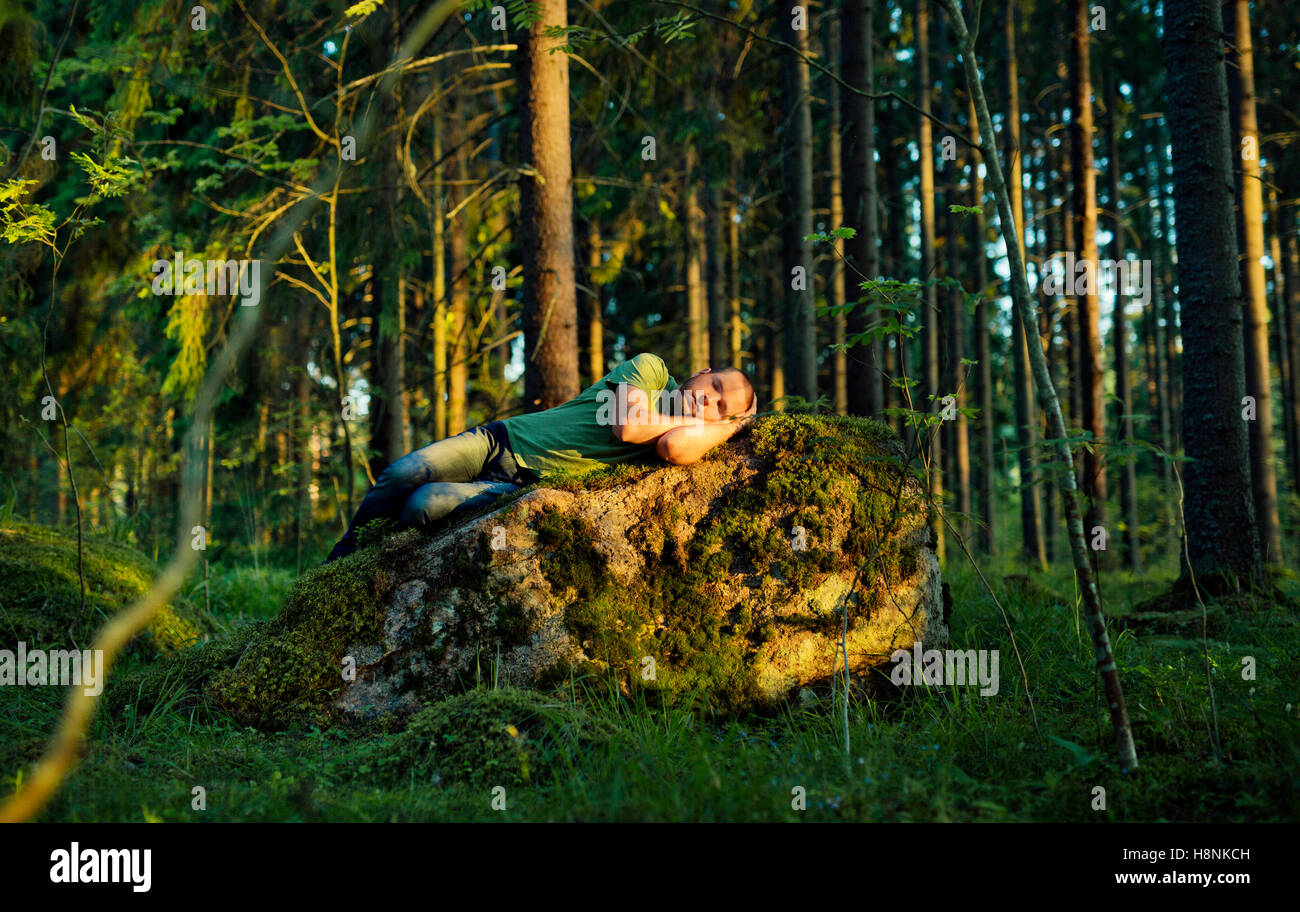 Man sleeping on moss covered rock in forest Stock Photo Alamy