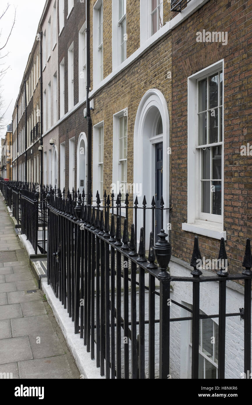 Black painted cast iron railings separate the pavement from the front facade of a terrace of Georgian houses in Doughty Street. Stock Photo