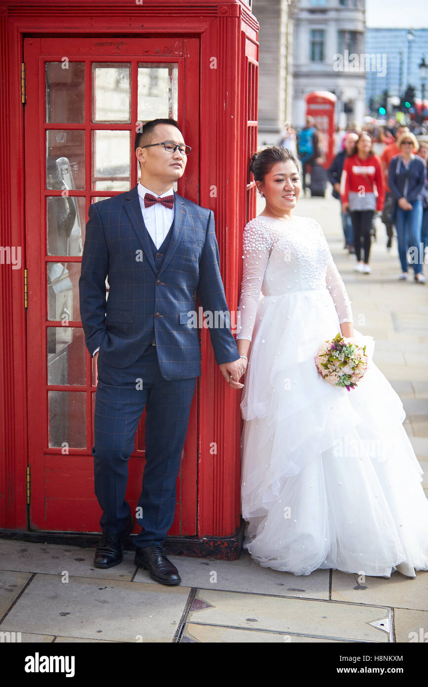 A Chinese couple pose for wedding photographs by a red telephone box in Parliament Square, London Stock Photo