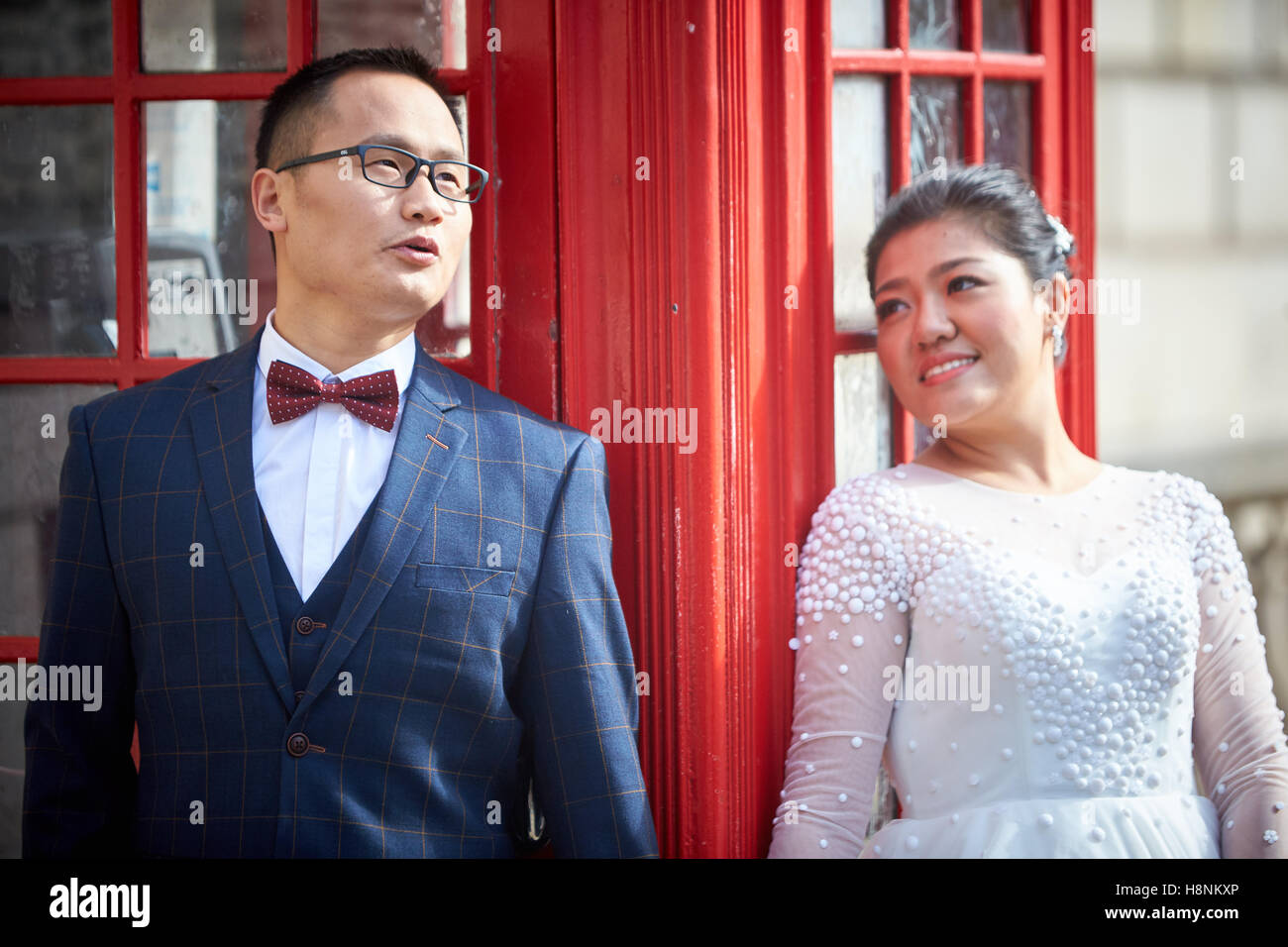 A Chinese couple pose for wedding photographs by a red telephone box in Parliament Square, London Stock Photo