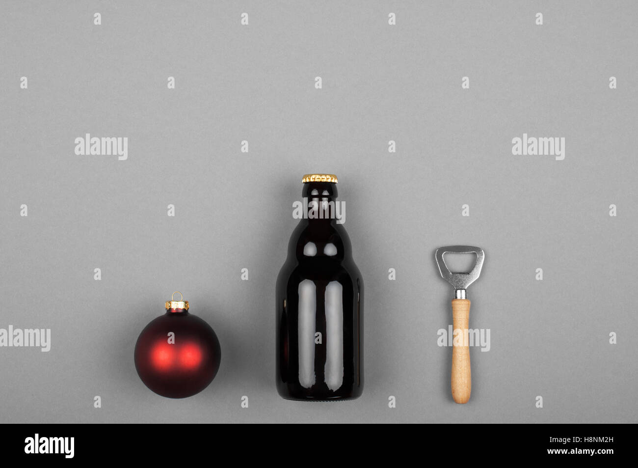 Beer bottle a christmas ball and a bottle opener over grey background Stock Photo