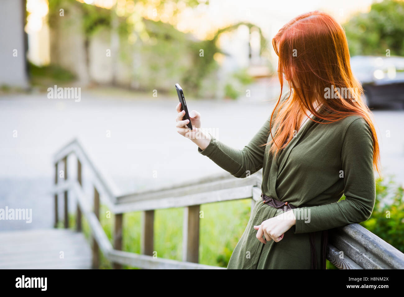 Redhaired woman standing on staircase and using phone Stock Photo