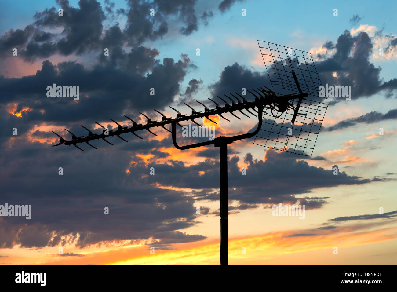 old TV antenna silhouette on evening blue cloudy sky background Stock Photo
