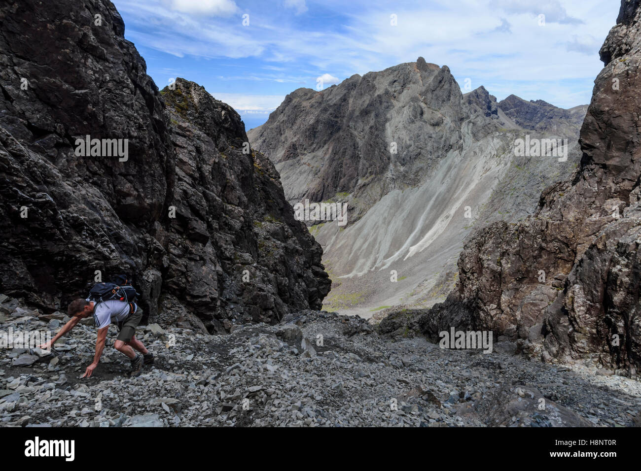 Male hillwalker ascending the Great Stone Shoot to reach the summit of Sgurr Alasdair (Munro), with views to Sgurr Dearg (The In Stock Photo