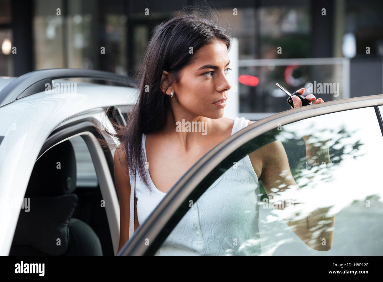 Attractive young woman standing near opened car outdoors Stock Photo