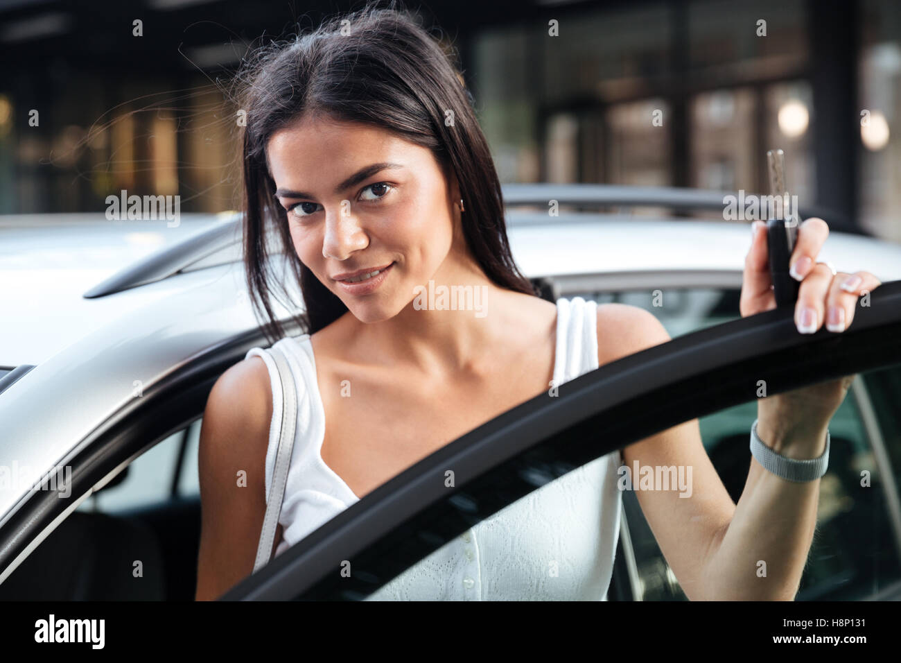 Closeup of beautiful young woman standing near opened car outdoors Stock Photo