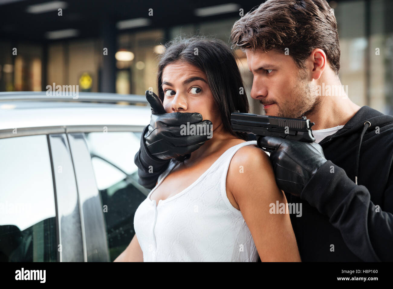 https://c8.alamy.com/comp/H8P160/dangerous-young-man-robber-in-gloves-covered-mouth-of-woman-and-threatening-H8P160.jpg