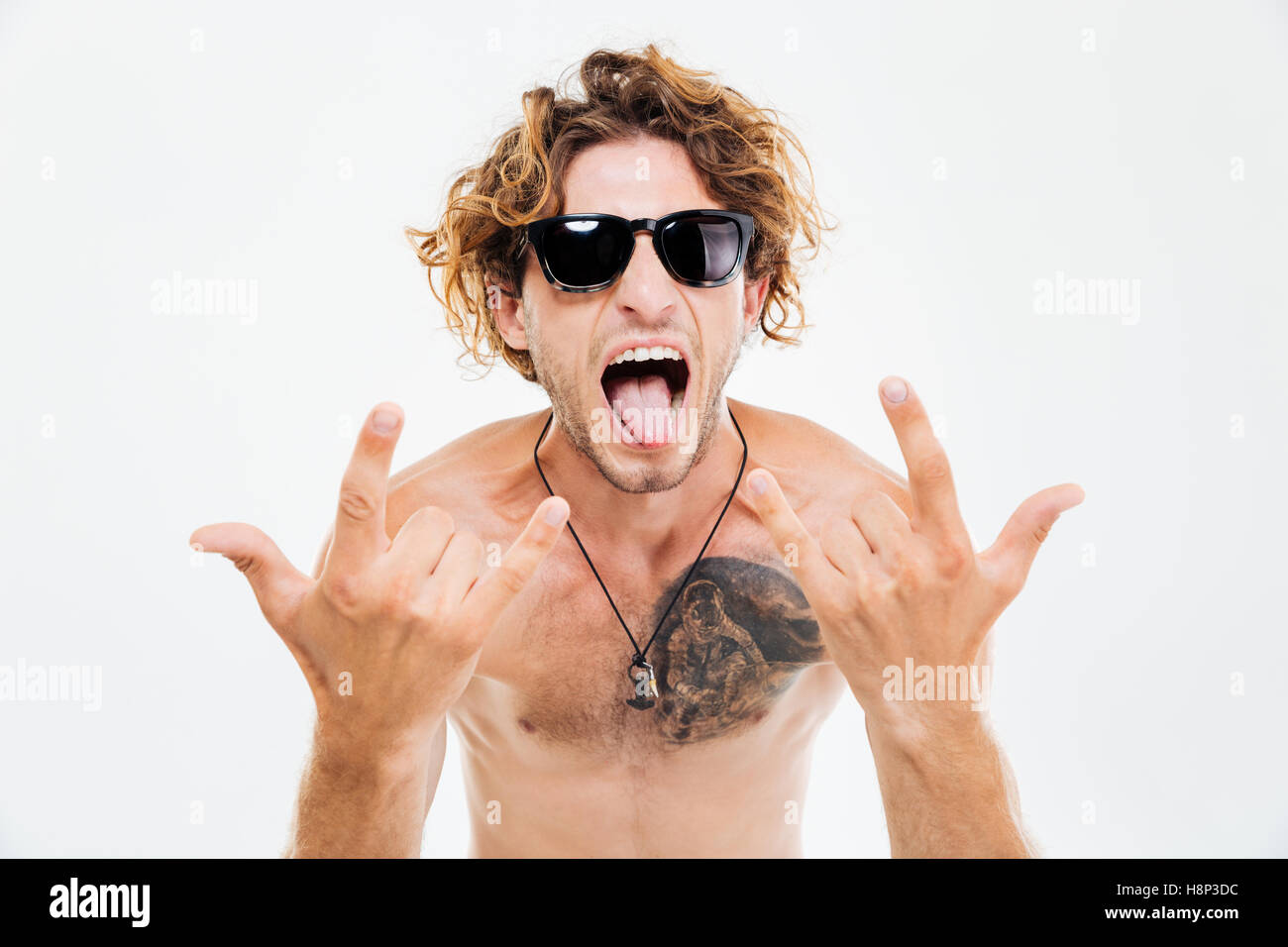 Crazy curly man in sunglasses showing tongue and rock gesture with hands isolated on the white background Stock Photo
