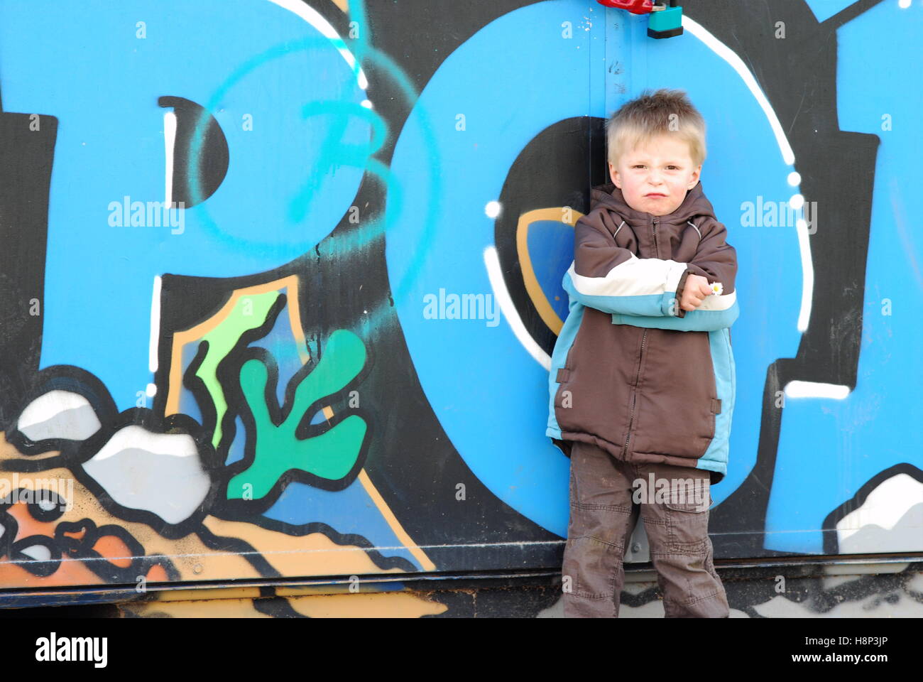 Cheeky toddler standing by some Graffiti wall. Stock Photo