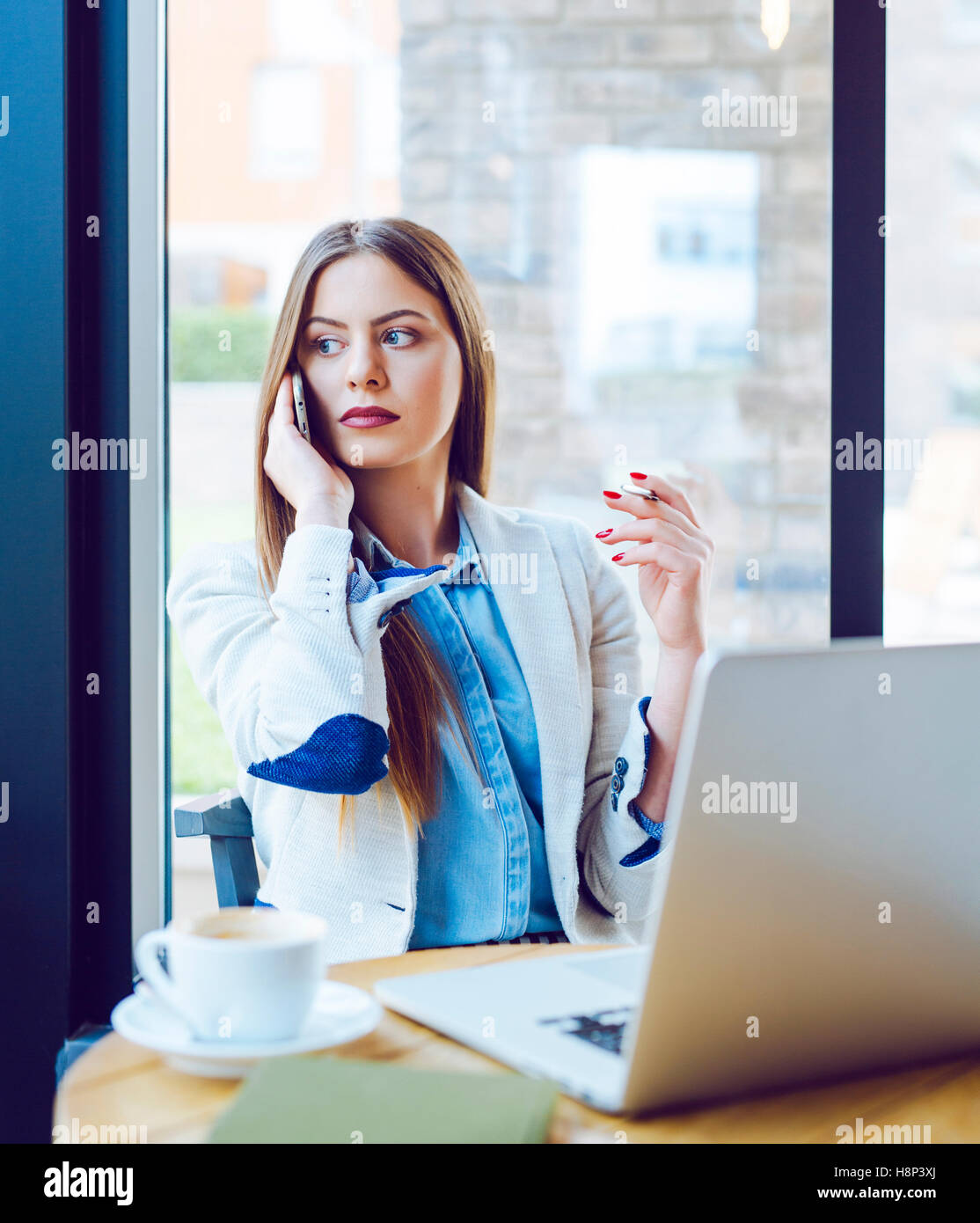 Beautiful Young Woman Sitting in Coffee Shop and Talking on the Phone Stock Photo