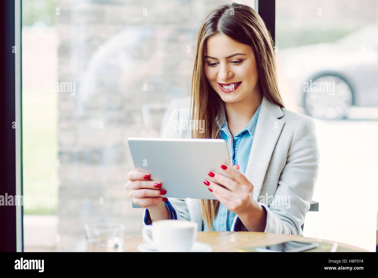 Young Woman Sitting in Coffee Shop and Working Stock Photo