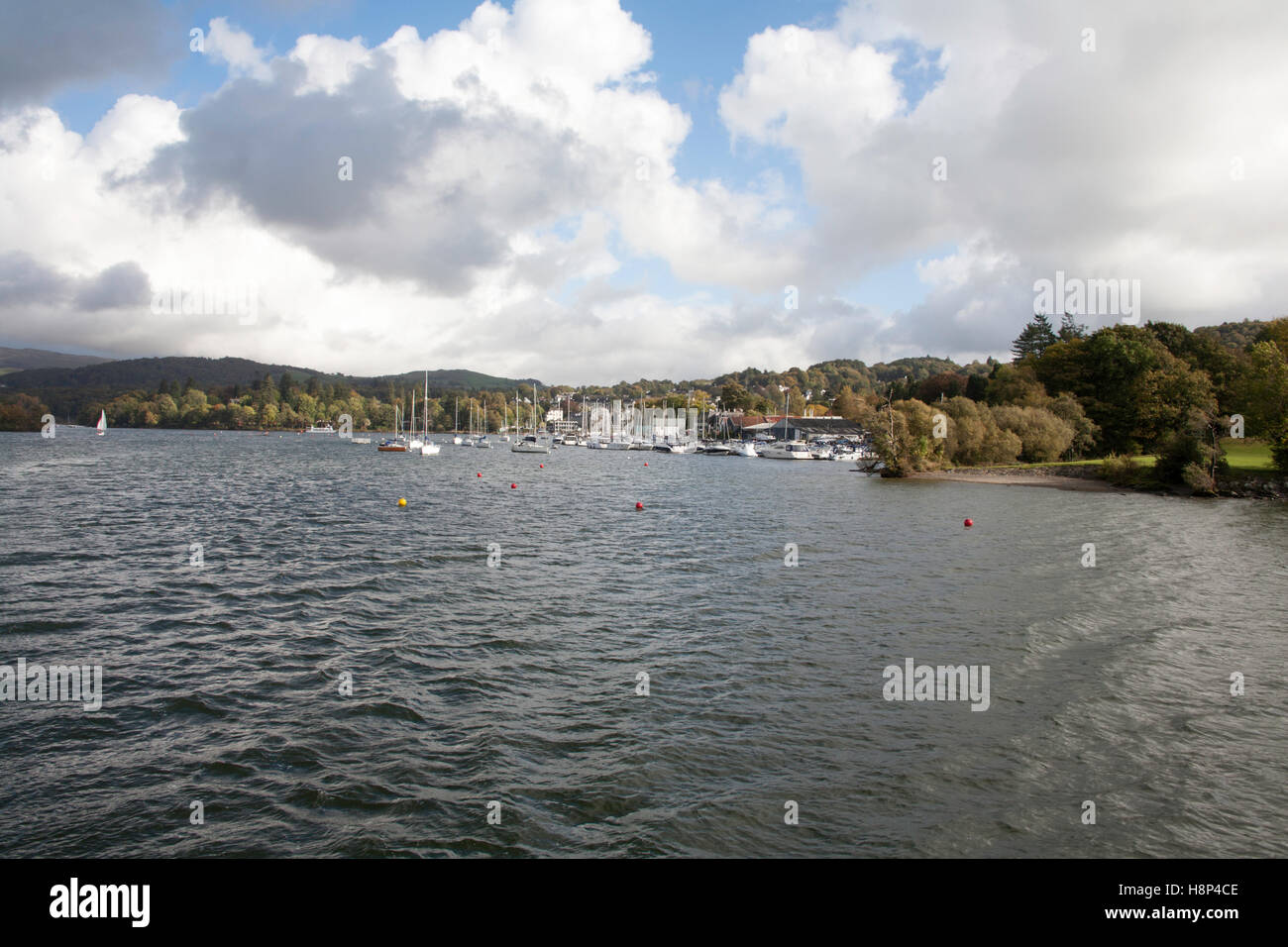 Boats moored near Ferry Nab Windermere with trees in Autumn colours Lake District Cumbria England Stock Photo