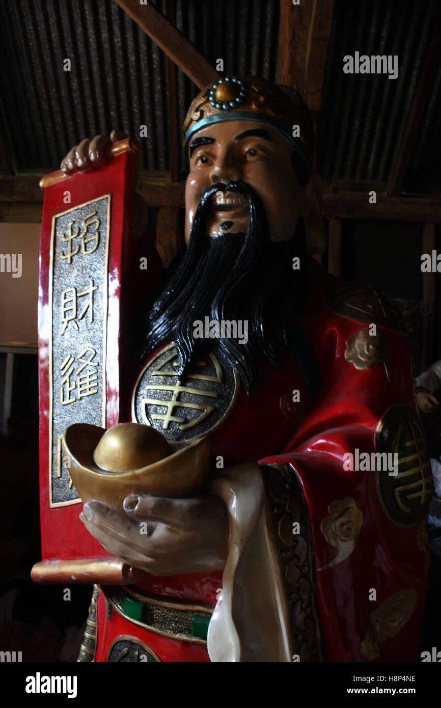 Chinese man statue in storage holding sign wearing red robes Stock Photo