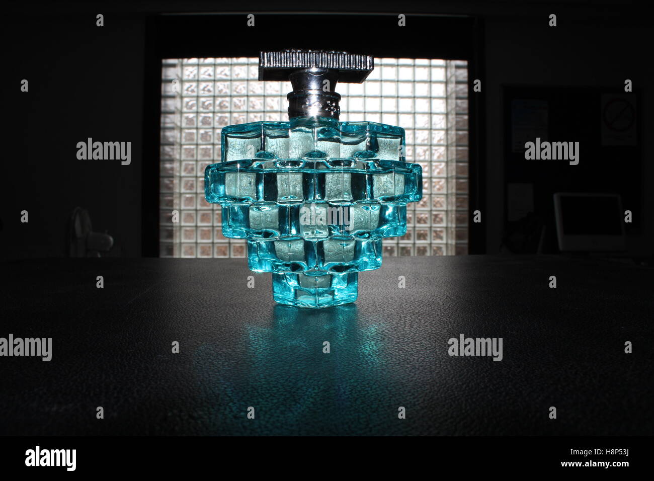 blue perfume bottle stood in front of a squared window Stock Photo