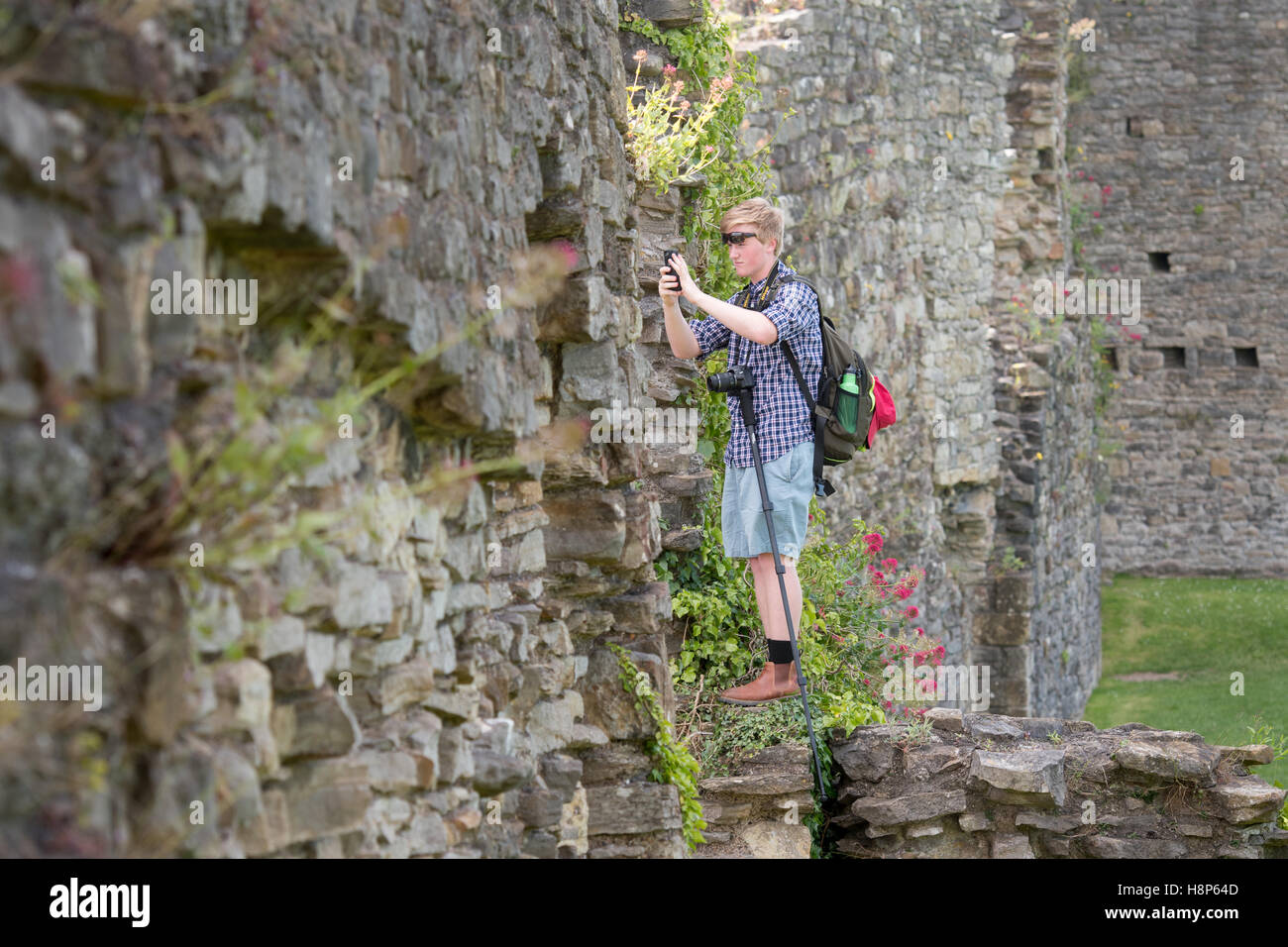 UK, England, Yorkshire, Richmond - A young male tourist taking pictures on his cell phone of the Richmond Castle, one of North Y Stock Photo