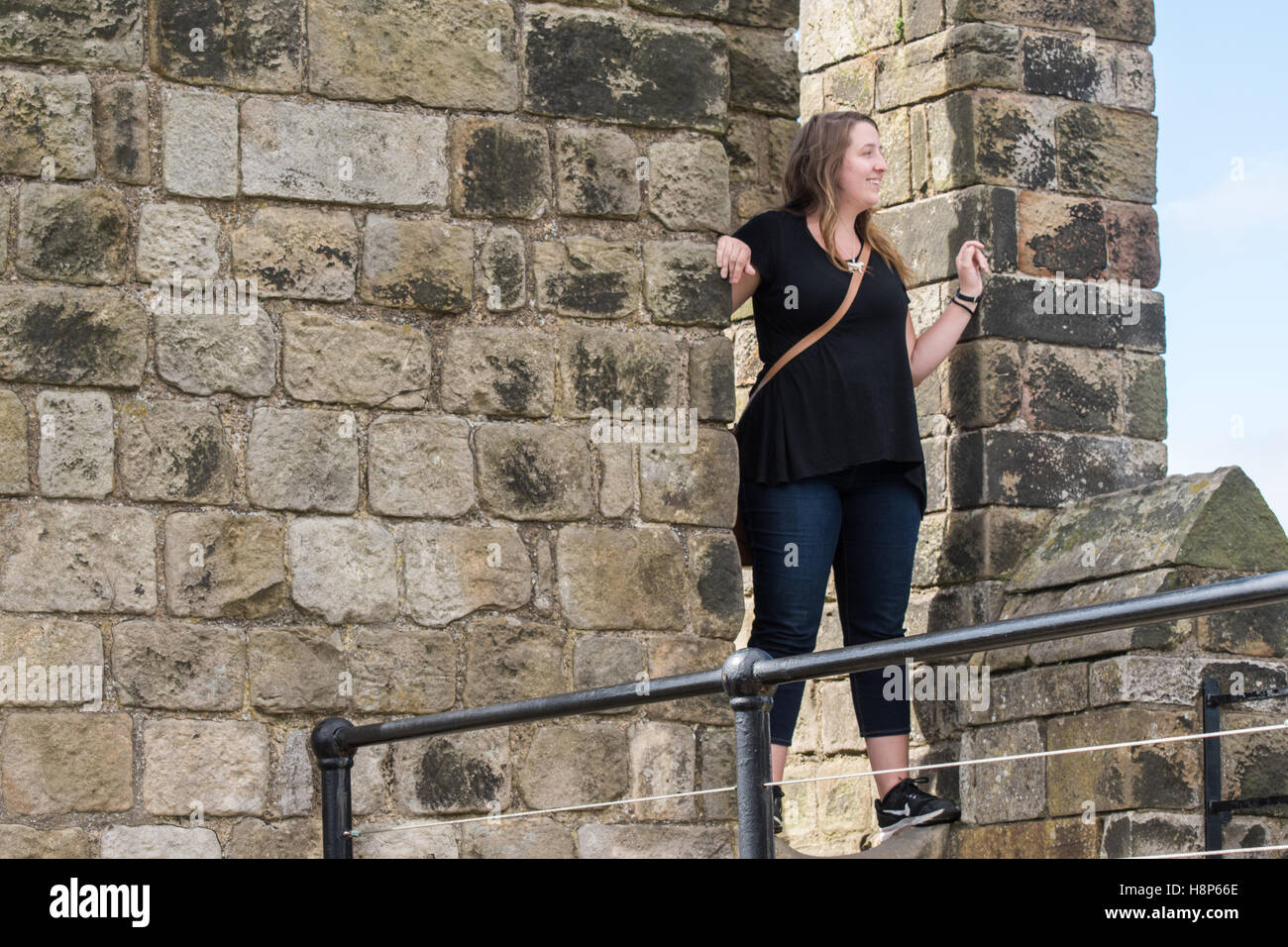 UK, England, Yorkshire, Richmond - A young female tourist posing in a doorway within the Richmond Castle, one of North Yorkshire Stock Photo