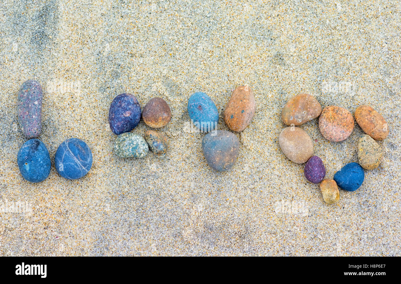 the word 'love' spelled out in stones lying on the sand. Stock Photo