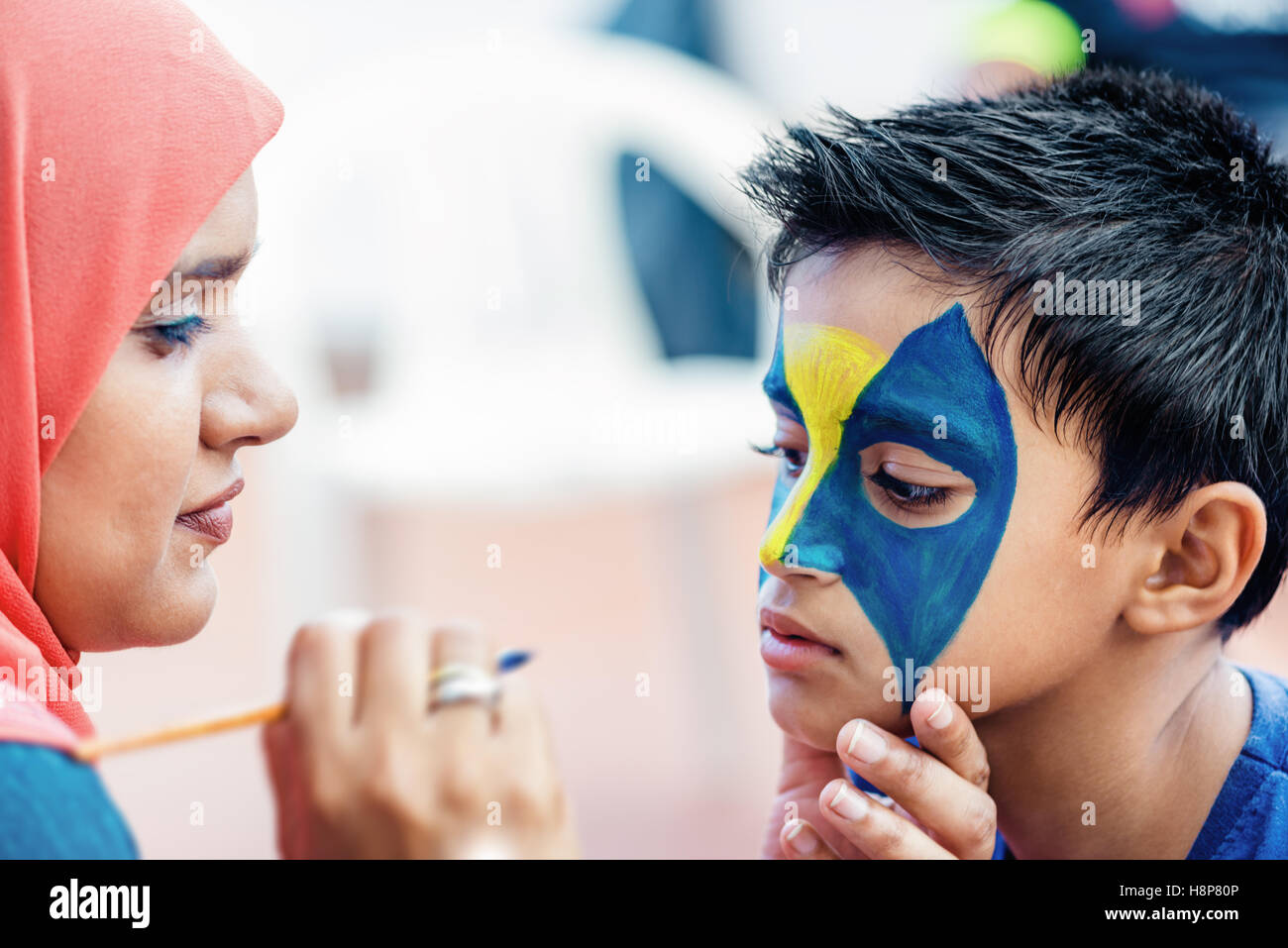 Boy child young having his face painted for fun at a birthday party Stock Photo