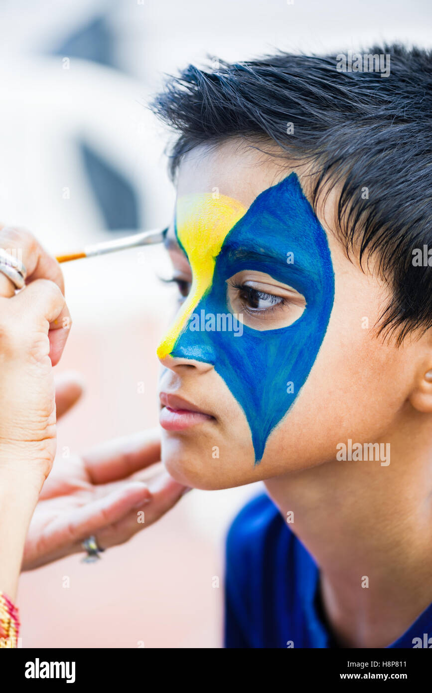 Nine year boy handsome child young having his face painted for fun at a birthday party Stock Photo