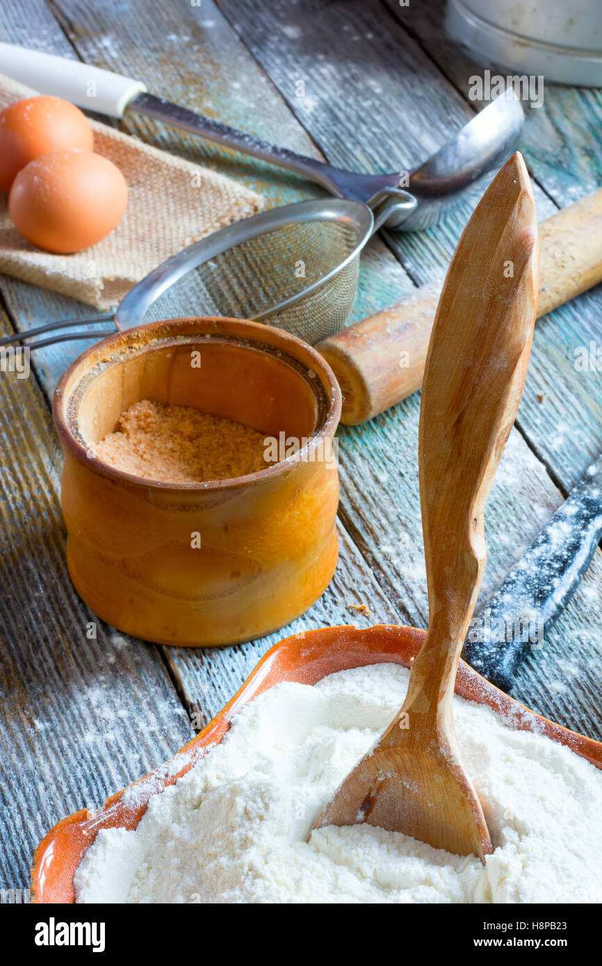 The wooden spoon stuck to the ceramic bowl with the flour, a jar with