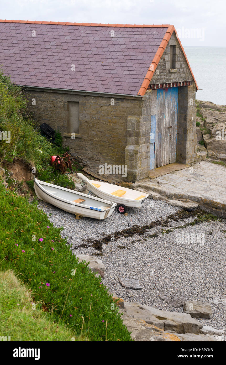 Stone boat house and small boats on a shingle beach in the village of Moelfre, Isle of Anglesey, North Wales, U.K. Stock Photo