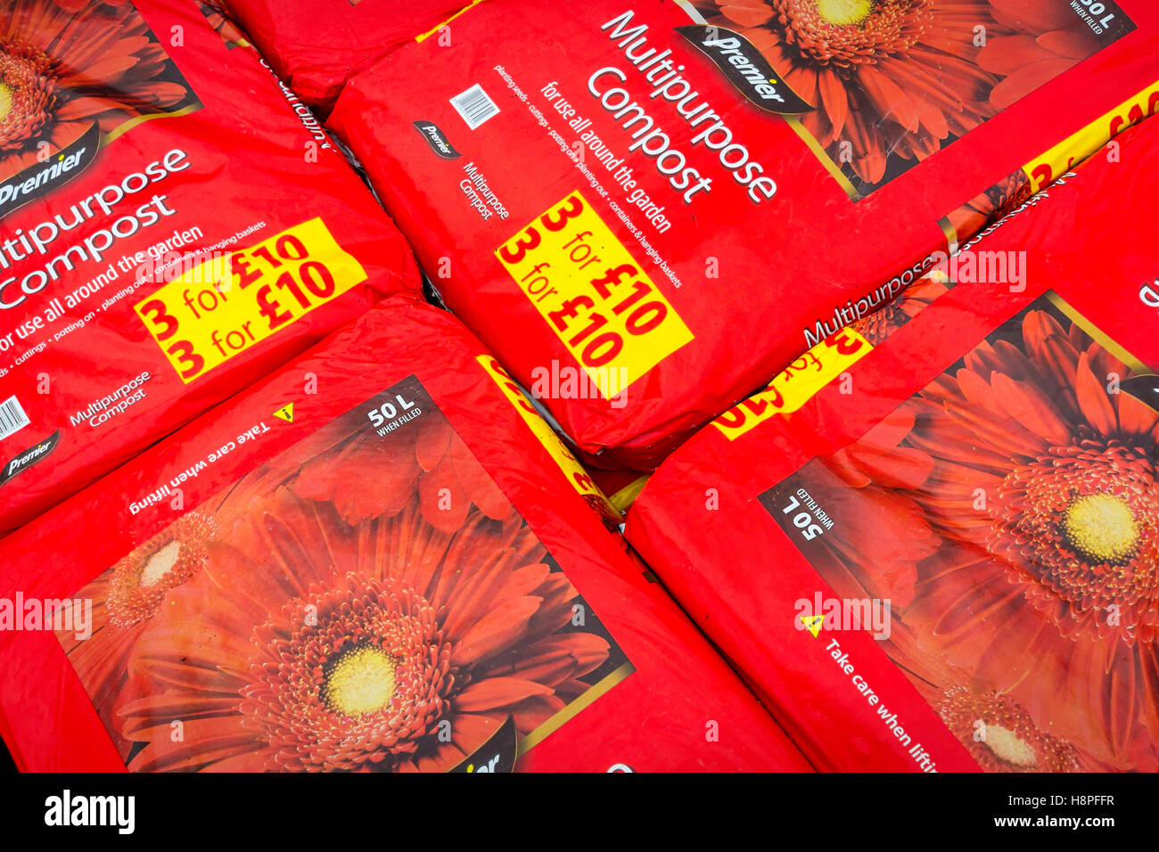 A stack of red bags of multipurpose compost in a garden centre Stock