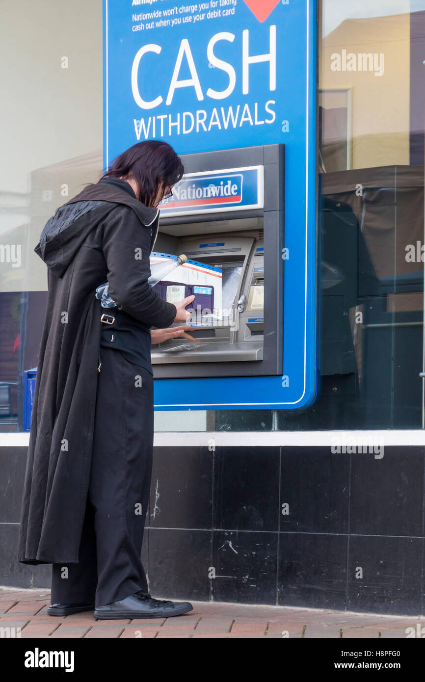 A man dressed in black withdrawing cash from a Nationwide Building Society  ATM or Cash Machine Stock Photo