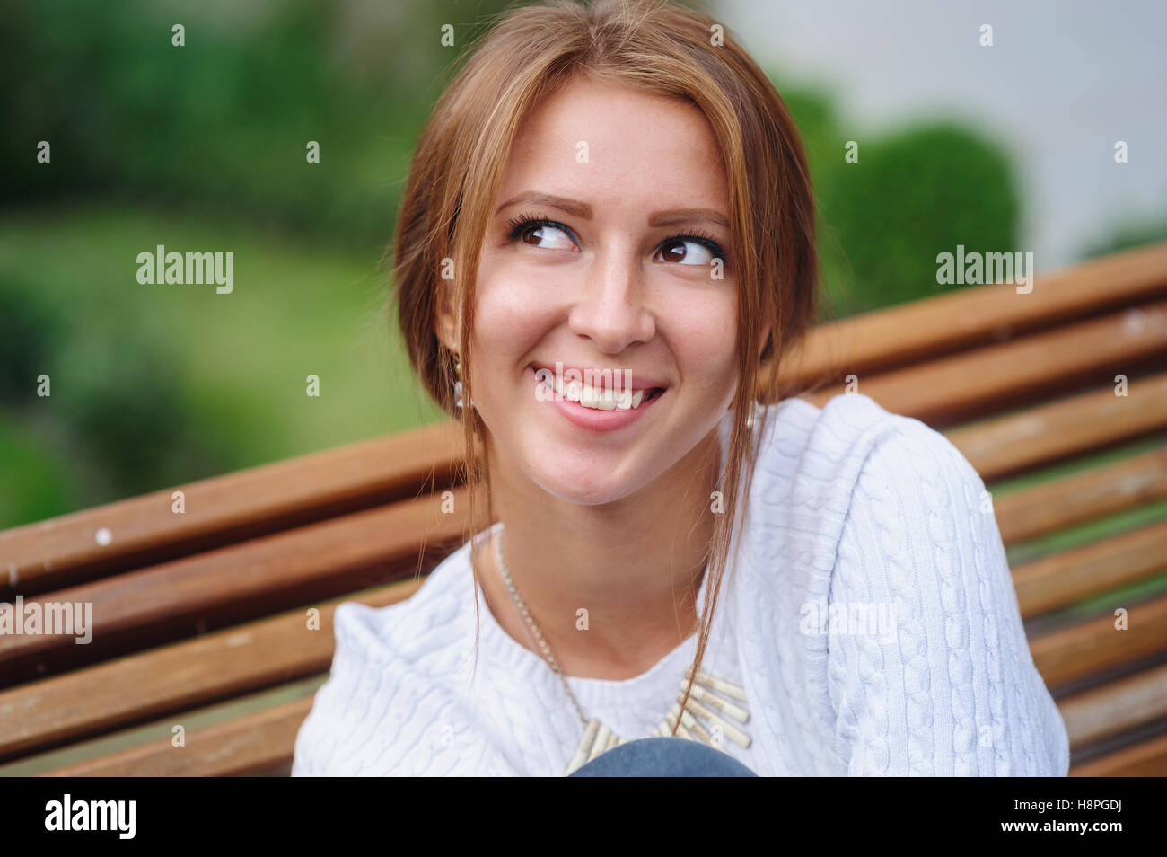 happy young woman sitting on a bench in the Park Stock Photo
