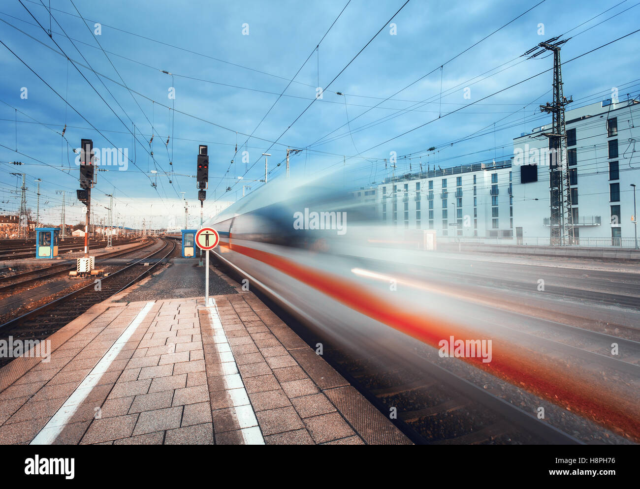 High speed passenger train on railroad track in motion. Blurred commuter train. Railway platform in the city. Railway station in Stock Photo
