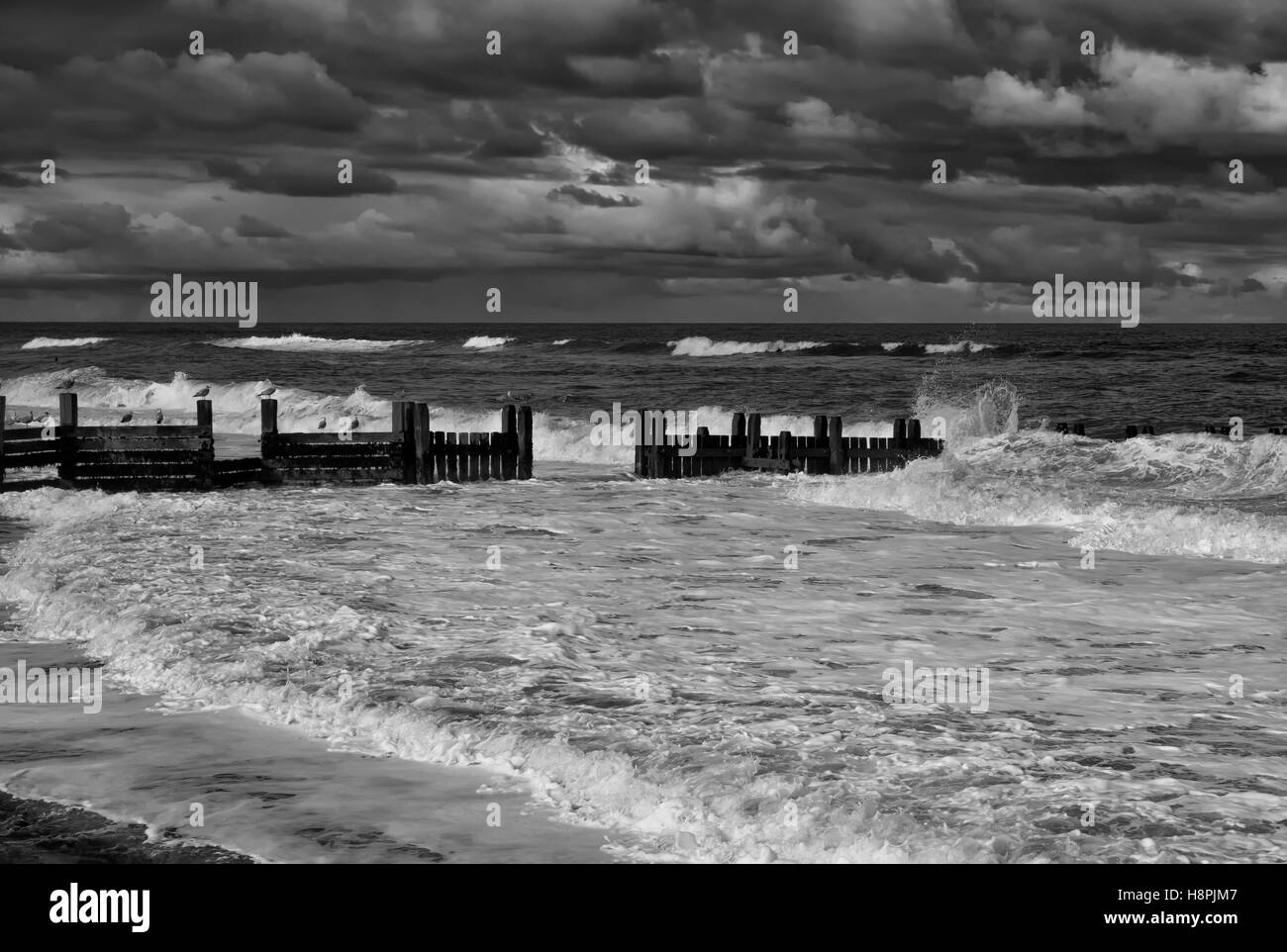 Waves breaking over the revetments sea defences on the North Norfolk coast Stock Photo