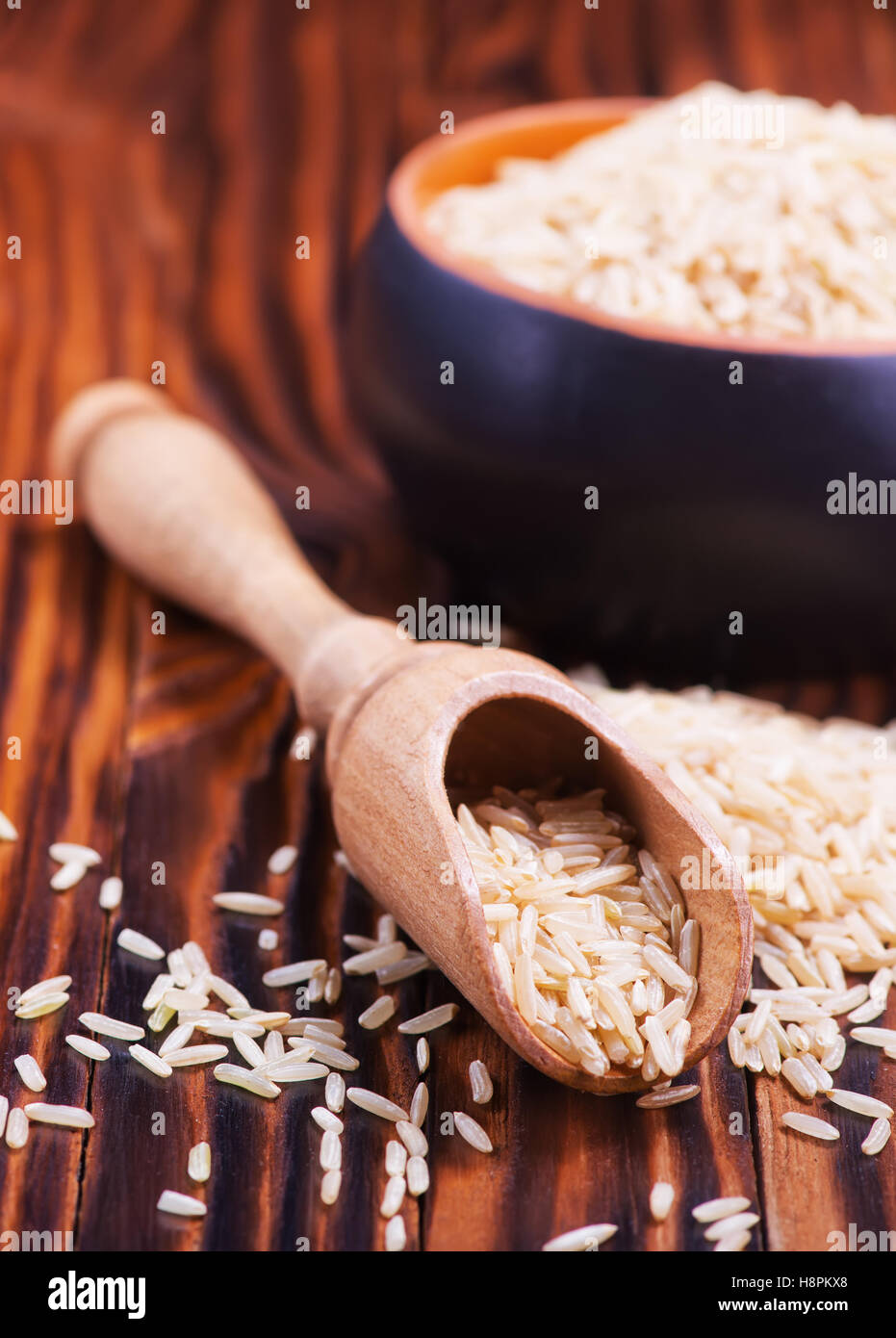raw rice in wooden spoon and on a table Stock Photo - Alamy