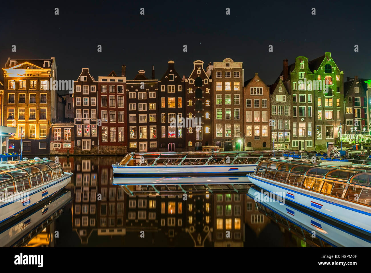 Bright cityscape with night lights reflection in water, architecture of Amsterdam, Holland Stock Photo