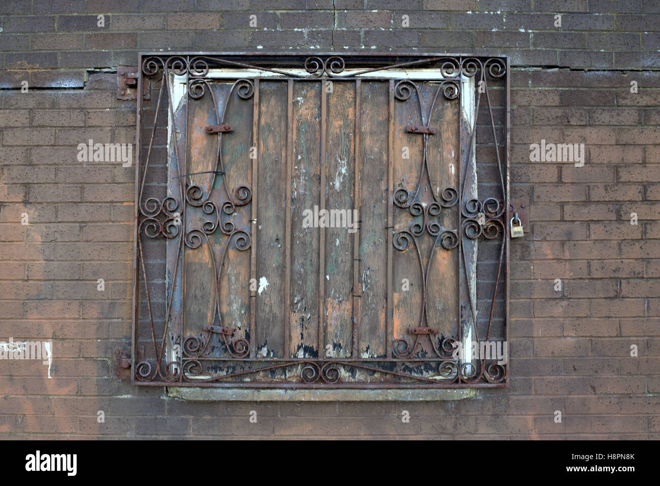 locked bars wrought iron window red rusty grill brick wall Stock Photo