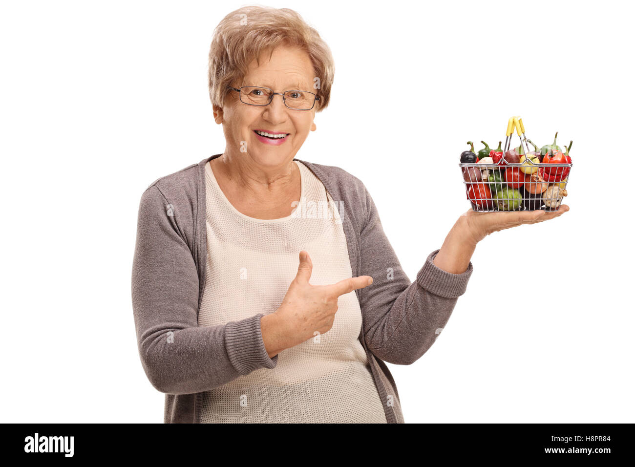 Elderly woman holding a small shopping basket full of fruits and ...