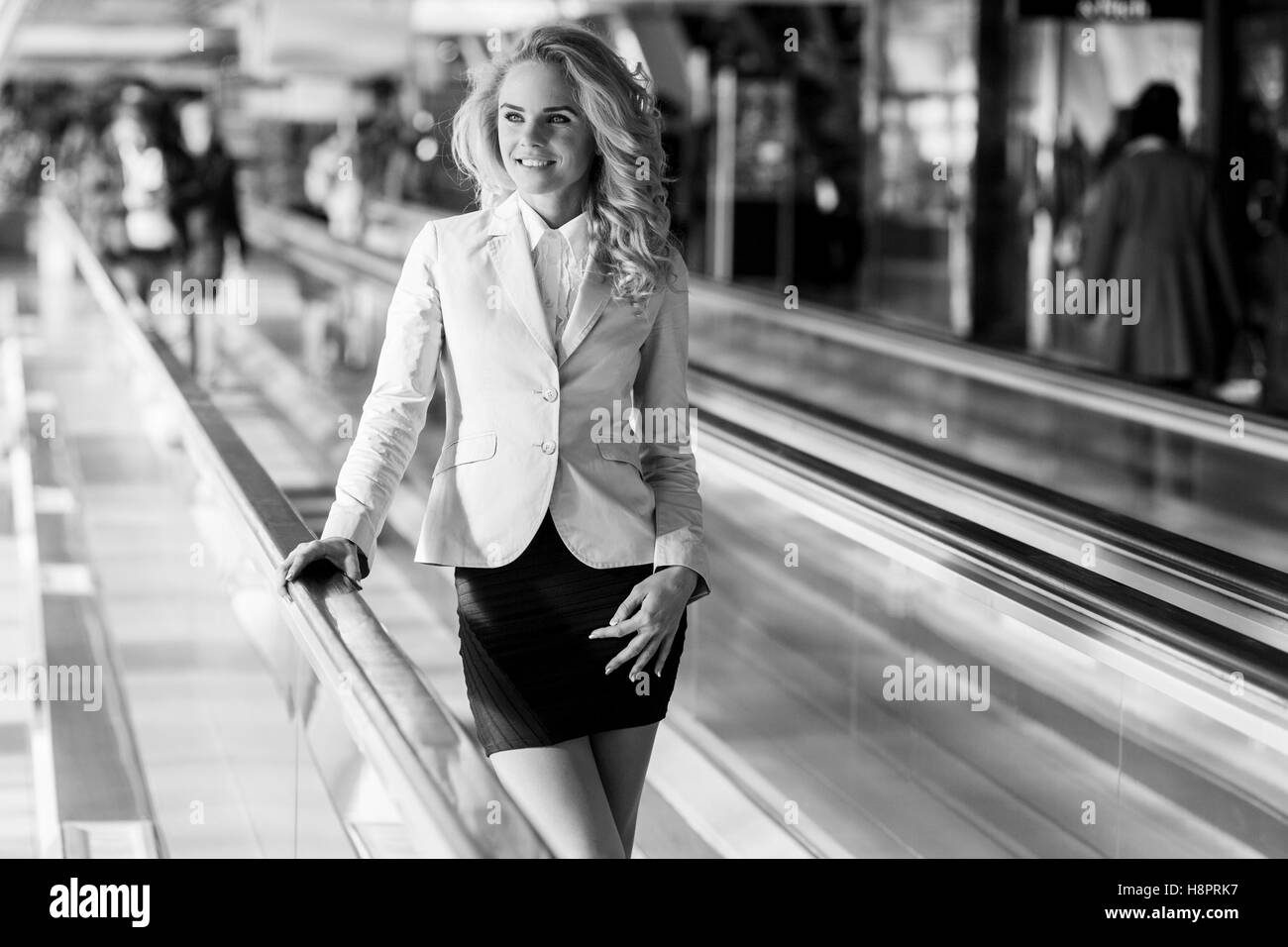 Black and white portrait of smiling woman on travelator indoor Stock Photo