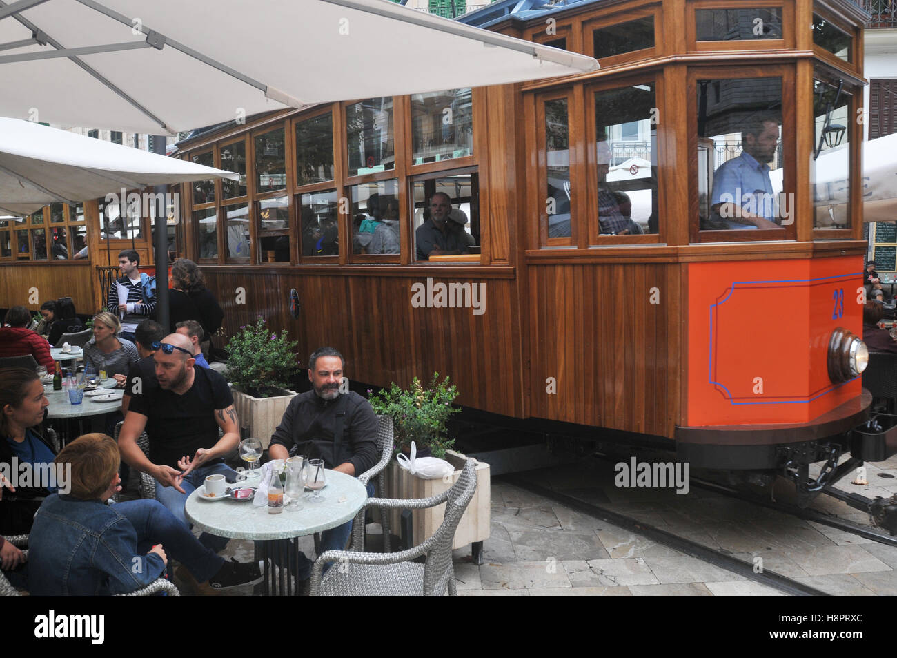 Tourists on the tram that runs from Soller to the port of Soller. Here it travels through the town, past cafes and bars. Stock Photo