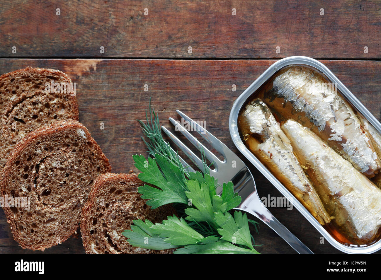 Canned fish near sliced bread on wooden background Stock Photo