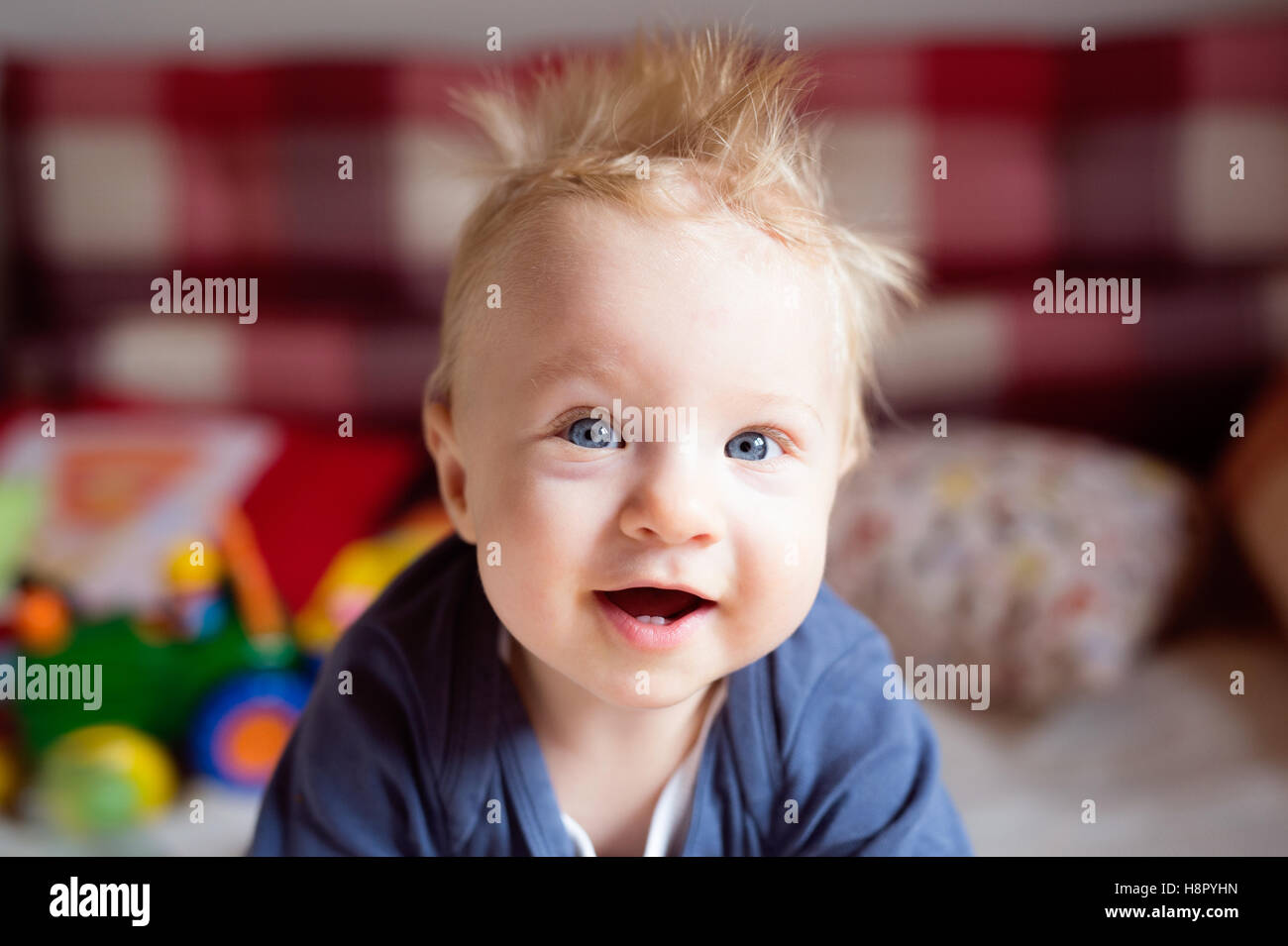 Little baby boy with spiky hair crawling on bed. Stock Photo