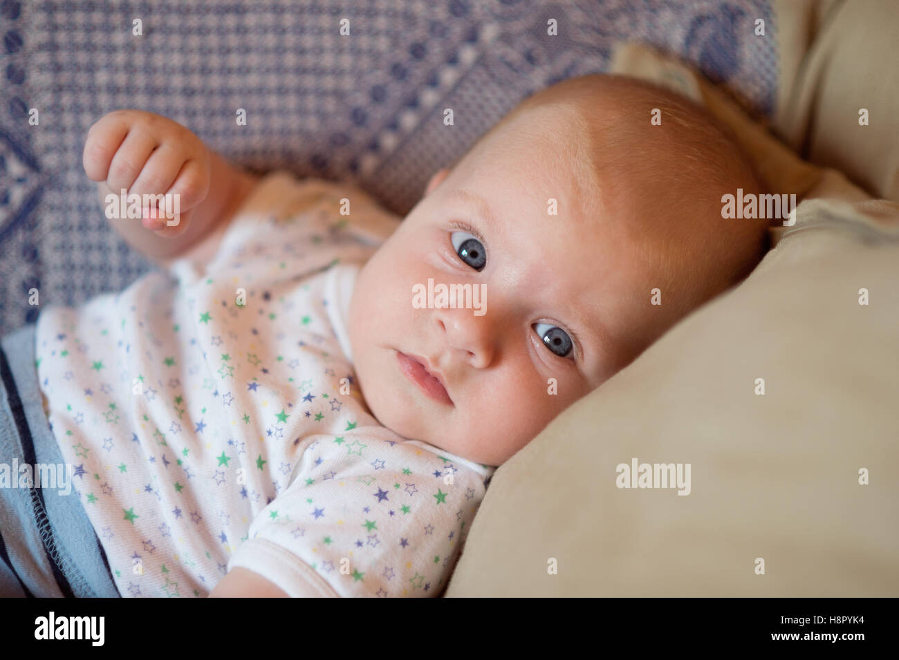 Little baby boy with big blue eyes lying on couch. Stock Photo