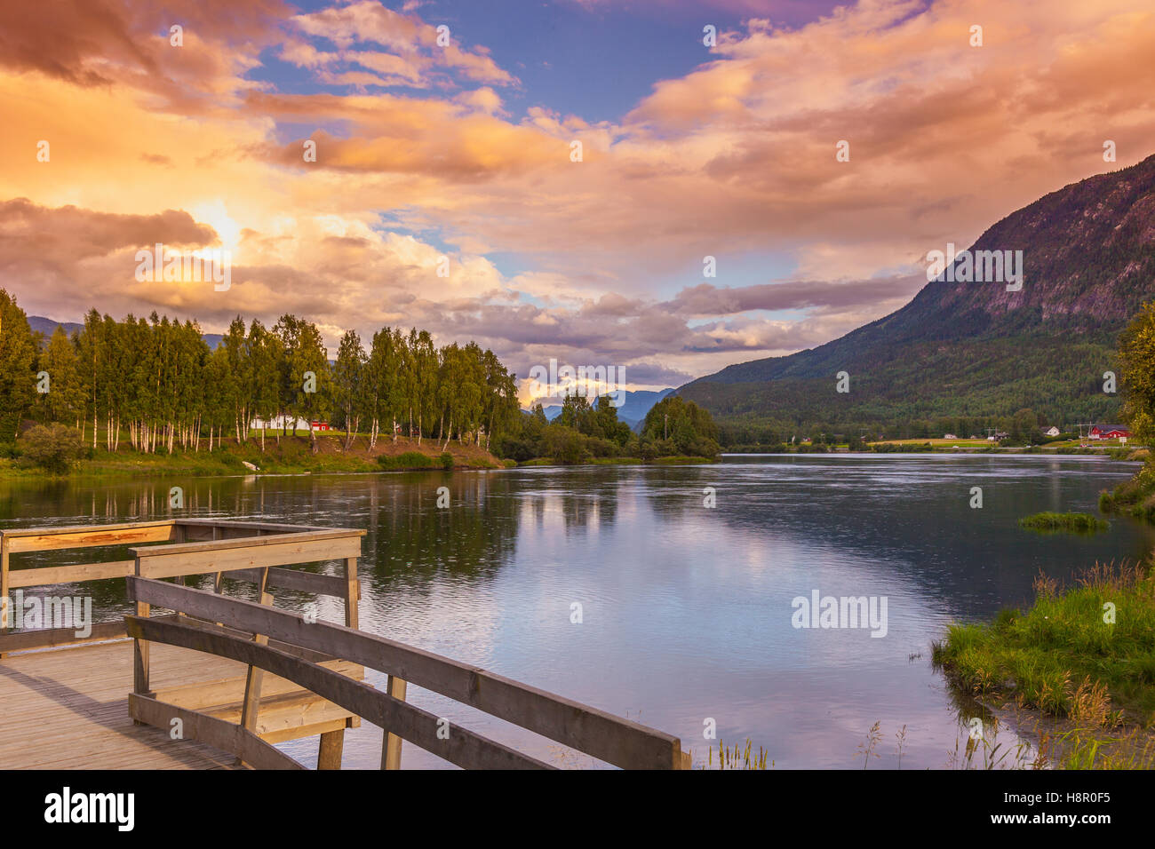 Sunseet pier at lake, pond among mountains under sunset twilight sky. Relaxation serene tranquility, vacations background Stock Photo