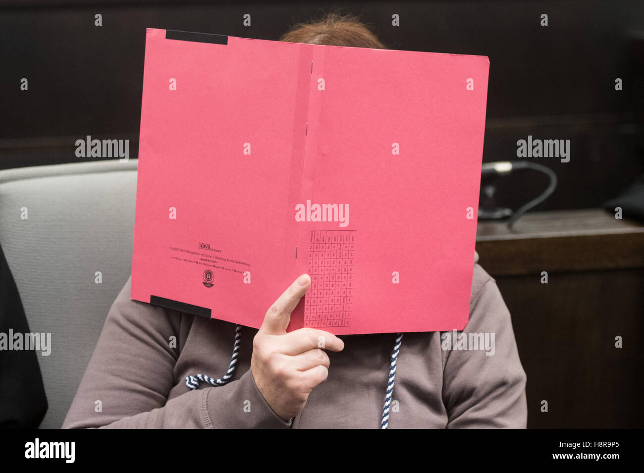 Paderborn, Germany. 16th Nov, 2016. The defendant Angelika W. hides her face behind a binder in the district court in Paderborn. The district attorney's office is accusing 46-year-old Wilfried W. and his one-year older ex-wife Angelika W. of two counts of murder through neglect as well as multiple counts of bodily injury. Both defendants allegedly used personal ads to lure women to their house in Hoexter-Bosseborn and severely abused several of them. Two of the women died as result of the ordeal, another woman escaped. Photo: BERND THISSEN/dpa/Alamy Live News Stock Photo