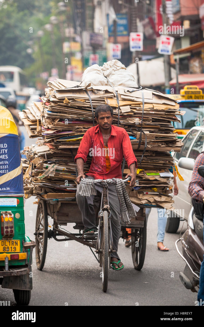 A cycle rickshaw in Old Delhi, India, transporting scrap carboard amongst busy motor traffic Stock Photo