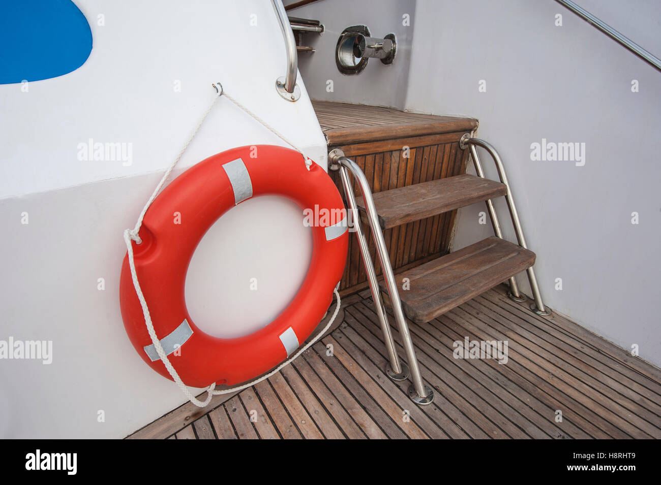 Safety equipment life buoy ring next to steps on teak deck of a luxury motor yacht Stock Photo
