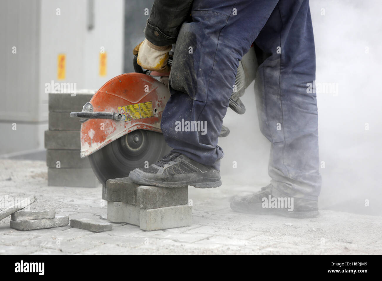 Worker uses a stone cutter to cut the brick pavers. Cutting concrete