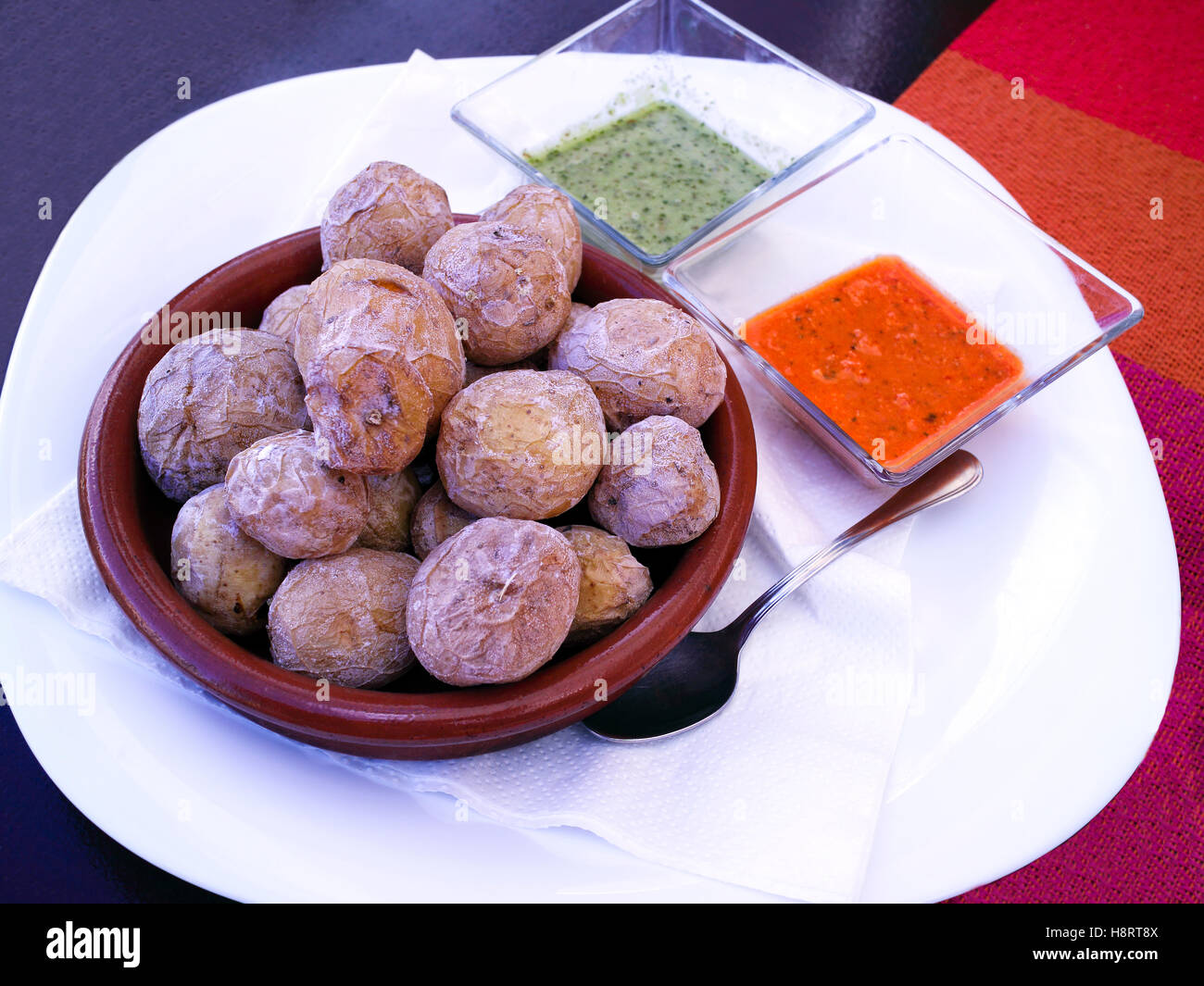 bowl of baked potatoes in skins served with spicy pepper and cilantro sauce Stock Photo